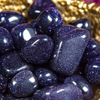 a bowl of black and purple stones on a gold plate