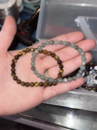 a person holding a pair of tiger eye beaded bracelets