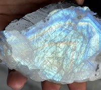 a person holding a piece of blue and white labradorite